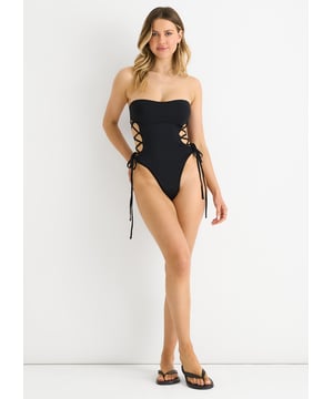 Mejora tu look playero con nuestro bañador bandeau negro con cordones laterales. Este moderno bañador presenta un favorecedor top bandeau, con laterales ajustables con cordones para un ajuste personalizado. El elegante diseño negro añade un toque de sofisticación a cualquier día de piscina o mar. Mantente cómoda y con estilo con este bañador imprescindible.