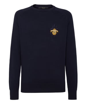 Este sofisticado jersey de cuello redondo combina a la perfección la comodidad con una elegancia discreta, lo que lo convierte en un básico versátil tanto para looks informales como elevados. Su confección de primera calidad garantiza un atractivo atemporal.   Confeccionado en algodón de alta calidad para un tacto suave y transpirable.   Presenta un sutil pero refinado escudo bordado que le da un toque de lujo.   Puños y dobladillo acanalados para un acabado elegante y a medida.    Ideal para llevar encima de camisas o solo para un estilo versátil.   Perfecta para combinar con pantalones de sastrería o vaqueros elegantes.