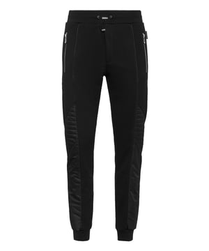 Descubra la originalidad de estos pantalones de chándal de forro polar de mezcla de algodón decorados con costuras únicas.   Vellón de mezcla de algodón   Detalles de nailon acolchado   Hexágono de PP en una insignia de cuero saffiano cosida en la espalda   Bolsillos abiertos con cremallera   Cintura de punto elástico con cordón de tope   Puños de punto elástico