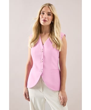 Sleek longline waistcoat with elegant button detailing down the front
        Flattering V-neckline that creates a sophisticated silhouette
        Practical side pockets for everyday functionality
        Tailored regular fit that complements the petite frame
        Versatile sleeveless design perfect for layering throughout the seasons
    
    This Wallis longline waistcoat presents a contemporary twist on classic tailoring, designed specifically for petite frames. The streamlined silhouette offers a sophisticated look that can be styled multiple ways for daywear occasions. Pair with wide-leg trousers as shown for a coordinated ensemble that projects confidence at family gatherings or lunch with friends. For a more casual approach, layer over a fitted turtleneck with your favourite jeans and trainers. The button detailing adds visual interest while the V-neckline frames the dcolletage beautifully. This versatile piece transitions effortlessly from office to weekend, making it an essential addition to your wardrobe. The regular fit ensures comfort throughout the day while maintaining a polished appearance that reflects the glamorous yet comfortable aesthetic Wallis is known for.