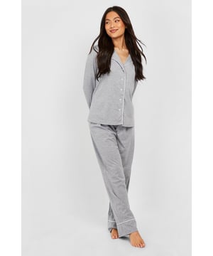 Stylish button-through jersey pyjama set
        Contrasting piping detail for a chic look
        Long sleeves with cuffed ends for extra comfort
        Wide-leg trousers for unrestricted movement
        Soft jersey fabric ensures a cosy night's sleep
    
    Indulge in the ultimate bedtime luxury with this long sleeve button-through jersey PJ set from Boohoo. Perfect for those who appreciate both style and comfort, this set combines a classic silhouette with modern details. The contrasting piping along the collar, cuffs, and trouser hems adds a touch of sophistication to your nighttime ensemble. The wide-leg trousers offer freedom of movement, ideal for restless sleepers or lazy weekend mornings. Whether you're having a girls' night in or simply unwinding after a long day, this versatile set is your go-to choice. Pair with fluffy slippers and a warm dressing gown for those chilly evenings, or wear the top with your favourite jeans for a casual daytime look. This PJ set isn't just for sleeping - it's for living your best, most comfortable life.
