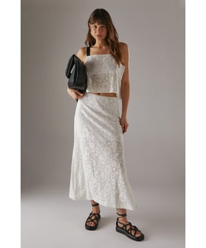 Intricate crochet column design creates a stunning textural effect
        Elegant maxi length with a flattering side split for ease of movement
        Fully lined for comfort and opacity
        Versatile high-waisted silhouette pairs beautifully with crop tops
        Relaxed fit with a flowing, feminine drape
    
    This Warehouse Tablecloth Crochet Column Maxi Skirt showcases artisanal craftsmanship with its detailed crochet pattern. The high-waisted design creates a flattering silhouette, while the side split adds a contemporary touch to this daywear essential. Style as seen with a matching crochet crop top and chunky strappy sandals for an effortlessly cool summer look. For cooler days, layer with an oversized leather jacket and ankle boots. Perfect for garden parties, weekend brunches or casual gatherings with friends. The cotton construction ensures breathability and comfort throughout the day. This versatile piece transitions seamlessly from daytime coffee dates to evening barbecues - simply switch your footwear and accessories to refresh your look.