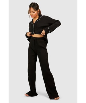 Ribbed jersey fabric for comfort and texture
        Tie waist detail for adjustable fit
        Wide-leg design for relaxed silhouette
        Matching cropped jacket with contrasting piping
        Versatile two-piece set for effortless lounging
    
    Embrace laid-back luxury with this rib tie waist lounge trouser set from Boohoo. Perfect for those cosy nights in or lazy weekend mornings, this ensemble offers both style and comfort. The wide-leg trousers feature a flattering high waist with an adjustable tie, allowing you to customise your fit. Pair with the matching cropped jacket, adorned with chic contrasting piping, for a coordinated look that's anything but ordinary. Whether you're binge-watching your favourite series or hosting an intimate brunch at home, this set will keep you feeling fabulous and relaxed. Style with soft slippers and your favourite oversized cardigan for ultimate comfort, or dress it up with statement earrings and a messy bun for those impromptu video calls. This Boohoo loungewear set is the epitome of effortless chic, ensuring you look put-together even on your most casual days.