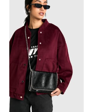 Edgy chain-trimmed design for a bold statement
        Versatile crossbody strap for hands-free convenience
        Compact size perfect for essentials
        Textured PU material with a distressed look
        Secure snap closure to keep belongings safe
    
    Make a striking impression with this edgy PU crossbody bag from Boohoo. The distressed texture and chain trim detailing along the edges create a rebellious vibe that's perfect for the fashion-forward trendsetter. Its compact size is ideal for carrying your essentials, while the crossbody strap offers hands-free convenience. Style it with a graphic tee and ripped jeans for a casual day out, or pair it with a little black dress for a night on the town. The versatile design makes it suitable for various occasions, from shopping trips to casual gatherings with friends. This bag is a must-have accessory that adds a touch of attitude to any outfit, allowing you to express your unique style with confidence.