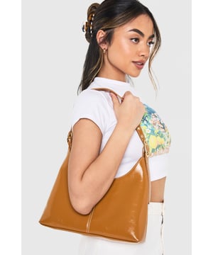 Sleek shoulder bag featuring distinctive contrast stitching detail
        Adjustable shoulder strap with gold-tone buckle fastening
        Compact yet spacious interior with branded lining
        Classic curved silhouette with minimalist design
        Versatile day-to-night accessory with secure top closure
    
    This chic shoulder bag combines timeless appeal with contemporary styling. The distinctive stitch detailing adds subtle texture to the smooth finish, while the curved silhouette creates an effortlessly sophisticated look. Style with a crisp white tee and high-waisted trousers for daytime errands, or pair with a fitted midi dress for evening drinks. The adjustable strap offers customisable comfort, making it perfect for all-day wear. Compact enough to remain unobtrusive yet roomy enough for essentials, this versatile bag transitions seamlessly from office to dinner date. The clean lines and understated design make it an ideal companion for both casual weekend brunches and more formal occasions, proving that the most stylish accessories are often the most versatile.