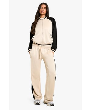 Striking colorblock design for a bold, sporty look
        Bomber-style jacket with full-length zip closure
        Straight-leg trousers for a comfortable, relaxed fit
        Ribbed cuffs and collar for a snug fit
        Versatile two-piece set for mix-and-match styling
    
    Make a statement in this eye-catching Trikot Colorblock Bomber-Trainingsanzug. The contrasting panels create a dynamic silhouette that's perfect for the fashion-forward trendsetter. The bomber-style jacket features a full-length zip, allowing for easy layering, while the straight-leg trousers offer both comfort and style. Pair the set with chunky trainers for an on-trend athleisure look, or split the pieces to create multiple outfits. Wear the jacket over a simple tee and jeans for a casual day out, or team the trousers with a cropped top for a night with friends. This versatile set is ideal for those busy days when you need to transition from running errands to meeting mates without missing a beat. The Boohoo Trikot Colorblock Bomber-Trainingsanzug is the perfect addition to your wardrobe, offering both style and practicality for the modern, active woman.