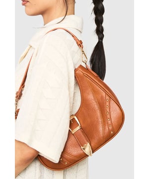 Stylish hobo bag featuring distinctive Western-inspired buckle detail
        Decorative metal studs along the sides for added flair
        Comfortable single shoulder strap with adjustable length
        Spacious main compartment with secure zip closure
        Gold-tone hardware accents throughout for a polished finish
    
    This versatile Western-detailed bag strikes the perfect balance between fashion and function for the modern woman on the go. The curved silhouette creates a relaxed yet chic aesthetic, whilst the statement buckle and stud embellishments add character to any ensemble. Pair with casual daywear-think relaxed jeans and an oversized jumper-for effortless weekend style, or match with a flowing midi dress and ankle boots for evening drinks. The practical size accommodates all your essentials without overwhelming your look, making it ideal for transitioning from office to evening plans. The adjustable strap offers customisable comfort whether worn close to the body or with a relaxed slouch. This boohoo bag is the ultimate day-to-night companion that complements virtually any outfit in your wardrobe.