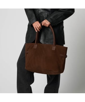 Crafted in a rich chocolate suede, this timeless tote from Barneys Originals combines luxury and functionality. The structured silhouette is complemented by smooth leather handles and elegant gold-tone trims. Spacious enough to hold all your daily essentials, it’s the perfect work or everyday bag.