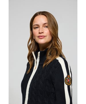 Unsere beliebte, von der Seefahrt inspirierte Strickjacke ist in einer neuen Ausführung zurück, ideal für moderne und elegante Frauen. Das gestickte Wappen auf dem Ärmel und die Kontraststreifen an den Ärmelabschlüssen, am Saum und am Reißverschluss sorgen für einen unverwechselbaren Touch. Der goldfarbene Frontreißverschluss mit exklusiver Logo-Zuglasche sowie der Stehkragen verleihen ihm eine moderne und funktionelle Note. Dieses Kleidungsstück ist die perfekte Ergänzung zu Jeans oder Chinohosen und verleiht jedem Freizeitlook Raffinesse.
