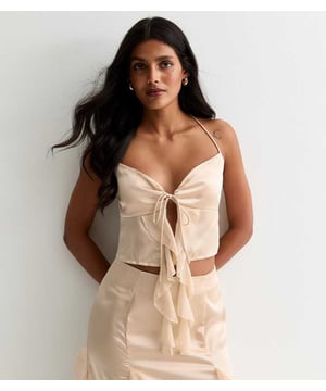 Indulge in luxury with our Champagne Satin Ruffle Tie Front Top. The smooth and lustrous satin fabric drapes elegantly and the ruffle and tie front details add a touch of sophistication. Perfect for any occasion, this top will make you feel glamorous and exclusive.