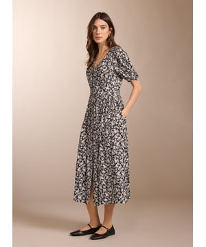 Description\nIf you love tea dresses then you’ll love Holly. This contemporary take in swishy crepe features a black and white ditsy print which goes effortlessly with denim and leather biker jackets. It has a flat waistband panel to the front and is smocked at the back for all-day comfort. With gathering around the shoulders, it’s a pretty midi dress to pair with ballet pumps or loafers.\n\nMade in Europe\nCrafted in LENZING™ ECOVERO™ crepe\nButtons through to the knee with rouleau loop fastenings\nElbow-length sleeves\nPockets in side seams\n\n\nSustainable Attributes:\n Low Water Use Ethically made  Vegan  \n\nDetails\nModel is 5'10 (177cm) and is wearing a UK 10100% LENZING™ ECOVERO™ ViscoseDelicate Machine Wash - 30°Product code: DR40569-BDTBack shoulder at neck to hem - 122cm (48)Sleeve length - 32.5cm (12 5/8)