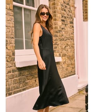 Description\nFits true to size, we suggest ordering your usual size.\nThe perfect satin slip dress does exist thanks to Nora! We’ve considered every detail of this timeless design to ensure it fits like a dream. Unlike classic slips, ours isn’t cut on the bias - so it won’t cling to the body. Instead, it simply skims and features a gently flared skirt. A scoop neckline and broad straps also means wearing a bra is no issue. Style it a million different ways: with sneakers and a denim jacket for casual days, or with heels and jewellery for date nights. It really is the ultimate LBD.\n\nMade in Europe\nCrafted in Ecojilin\nConcealed centre back zip\nLong midi length\n\n\nSustainable Attributes:\n  Low impact  Low Water Use   Natural fibres   Ethically made\n\nDetails\nModel is 5'10 (177cm) and is wearing a UK 10100% Ecojilin ViscoseDry Clean OnlyWash Inside Out - Wash Dark Colours SeparatelyProduct Code: DR40609-BLKBack shoulder at neck to hem - 121cm (47 3/4)