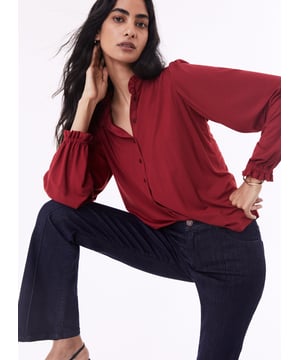 Description\nFits true to size, however if you are inbetween sizes, we suggest you size down.\nSima is a frill-adorned take on our best-selling Imken blouse. This feminine shirt features a relaxed collar with a ruffled trim - a detail that’s echoed in the elasticated cuffs. Cut from planet-conscious jersey for easy, all-day comfort, it’s a hard-working style to see you through work days and weekends.\nLove Sima for wearing solo or under knits - Baukjen\n\nMade in Europe\nCrafted in LENZING™ ECOVERO™ jersey\nRelaxed fit\nGathered detail around the shoulders\n\n\nSustainable Attributes:\n\n  \n Low Impact \n\n Low Water Use \n  \n Natural fibres \n   Ethically made\n\n Low Carbon \n\nDetails\n95% LENZING™ ECOVERO™ Viscose, 5% ElastaneDelicate Machine Wash - 30°Product code: JB40007-PWHBack shoulder at neck to hem - 62cm (24 2/5)Sleeve length - 62cm (24 2/5)