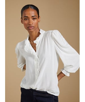 Description\nIf a feminine blouse is your thing, then you won’t be able to resist Aurora! This style is all you need to elevate a pair of jeans, thanks to the soft ruffle trim adorning the collar and placket. The fabric is special too: in a semi-sheer textured spot jacquard, proudly makes use of surplus fabric.\n\nMade in Europe\nCrafted in fine woven jacquard fabric\nButtons through\nElasticated cuffs\n¾ Length gathered sleeve detail\n\n\nSustainable Attributes:\n  Low Impact   Low Water Use  Ethically made  Low Carbon  \n\nDetails\nModel is 5'10 (177cm) and is wearing a UK 10100% ViscoseDry Clean Only Product code: SH40285-CREBack shoulder at neck to hem - 60cm (23 5/8)Sleeve length - 64cm (25 1/4)