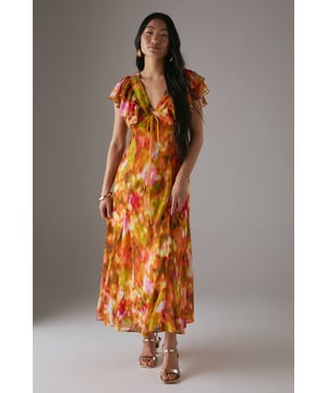 Feminine V-neckline with delicate tie-front detail for adjustable styling
        Romantic flutter sleeves with frilled edges adding movement and dimension
        Flowing midi length tea dress silhouette that flatters the figure
        Vibrant floral print pattern perfect for seasonal daywear
        Lightweight woven fabric with gentle drape for all-day comfort
    
    This captivating Warehouse tea dress combines effortless femininity with contemporary flair. The flattering V-neckline features a charming tie-front detail that allows for customised styling, while the delicate flutter sleeves with frilled edges create a soft, romantic silhouette. The flowing midi length offers versatile wear - pair with strappy sandals as seen on our model for casual brunches or garden parties, or dress down with white trainers for weekend shopping trips. The vibrant floral pattern makes this piece a standout addition to your daytime wardrobe. Perfect for family gatherings or casual meet-ups with friends, this dress transitions beautifully from spring through summer. Layer with a denim jacket and ankle boots during cooler months for extended seasonal wear.