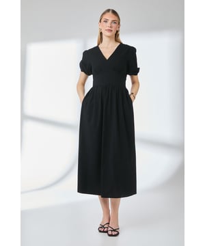 Elegant V-neckline with flattering gathered detail at the bust
        Practical side pockets for effortless everyday wear
        Midi length design offering versatile styling options
        Button detail adds subtle visual interest to this timeless piece
        Short puffed sleeves create a feminine silhouette with comfortable movement
    
    This linen-look midi dress combines simplicity with thoughtful design elements for a wardrobe staple that transitions seamlessly between occasions. The gathered waist creates a flattering shape while the relaxed skirt drapes beautifully for comfortable all-day wear. Style with strappy sandals as seen on our model for casual daytime events, or customise for evening gatherings with statement jewellery and a structured clutch. Perfect for family celebrations, weekend brunches or garden parties, this versatile dress works equally well with flat sandals for a relaxed look or dressed up with espadrille wedges. The natural-look fabric offers breathability and comfort, making it an ideal choice for warm weather occasions whilst maintaining a polished appearance.