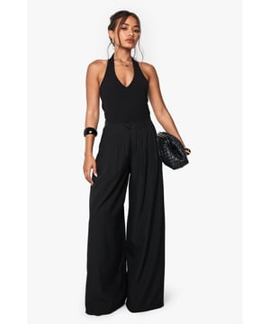 Extreme wide leg design creates a dramatic silhouette that flows beautifully with movement
        Halterneck top with plunging V-neckline offers a flattering and feminine touch
        Practical side pockets add functionality without compromising on style
        Pleated front detailing adds texture and dimension to the overall look
        Backless design creates a striking statement when viewed from behind
    
    Make a bold fashion statement with these eye-catching extreme wide leg trousers from Boohoo. The flowing silhouette creates a sense of drama and movement that's perfect for those who love to stand out. Style with chunky platform trainers for a casual daytime look, or dress up with strappy heels for evening gatherings. The halterneck design and backless feature add a touch of sophistication, making these trousers versatile enough for family brunches or casual meet-ups with friends. Accessorise as shown with statement bangles and oversized earrings to complete the look. The comfortable fit ensures you'll feel as good as you look, while the wide leg design creates an effortlessly chic vibe that's right on trend. Perfect for those who appreciate fashion-forward pieces that combine comfort with head-turning style.