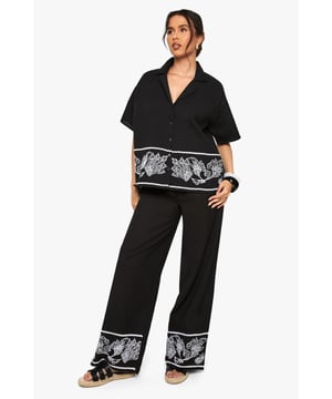 Cotton poplin wide leg trousers featuring striking embroidered border detail
        Relaxed silhouette with comfortable high-rise waistband
        Matching embroidered short-sleeve shirt creates a coordinated set
        Breathable cotton fabric ideal for warm-weather styling
        Versatile wide leg cut that flatters all body shapes
    
    Make a statement in these eye-catching embroidered wide leg trousers from Boohoo. The striking contrast border detailing adds artistic flair to this casual yet sophisticated piece. Crafted from breathable cotton poplin, these trousers offer both comfort and style for your everyday wardrobe. Style them as shown with the matching embroidered shirt for a coordinated look that's perfect for summer gatherings, or pair with a simple vest top and trainers for a more relaxed daytime ensemble. The wide leg silhouette creates a breezy, effortless feel that works brilliantly with flat sandals as pictured. For cooler evenings, layer with a denim jacket and accessorise with a woven bag to complete this contemporary casual look. These trousers transition seamlessly from beach holidays to city breaks, offering versatility for the fashion-forward woman.