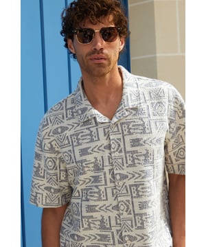 Freshen up your summer wardrobe with this tribal print relaxed fit shirt from Threadbare. This short sleeve printed shirt cut in a relaxed fit is an essential for bringing a bit of style to your outfit. Made from a textured fabric and finished with a revere style collar and button through fastening. Team in the daytime with denim shorts, or smarten up with a pair of chino shorts.