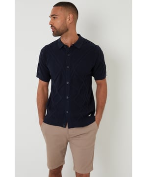 Combine classic style with modern comfort with this knitted polo shirt from Threadbare. With a ribbed placket with button-through fastening, this shirt has a Milano stitch collar and ribbed cuffs and hem. In an all-over textured knit, made from a cotton blend yarn and finished with a metal Threadbare tab above the hem. Pair with chinos or jeans for everyday wear or team with shorts for summer style.