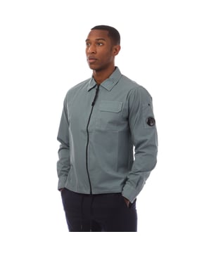 Mens C.P. Company Organic Gabardine Full Zip Overshirt in grey.- Classic collar.- Long sleeves.- Adjustable button cuffs.- Chest flap pocket.- Lens detail.- Garment dyed.- Regular fit.- 100% Cotton.- Ref: 18CMOS124A872