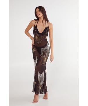 Striking celestial embellishment with shimmering tassel details throughout the dress
        Elegant cowl neckline with delicate strappy back design
        Flowing maxi length with a subtle flare at the hem
        Semi-sheer fabric offering a sophisticated beach-to-bar versatility
        Flattering body-skimming silhouette that moves gracefully with every step
    
    This enchanting Celestial Embellished Tassel Detail Cowl Maxi Dress from Nasty Gal captures the essence of luxurious beachwear. The dramatic cowl neckline frames the dcolletage beautifully, whilst the strappy back adds an alluring touch. Style with metallic sandals and a woven beach bag for daytime lounging by the pool. As the sun sets, transform your look with statement gold jewellery and a sleek clutch for evening cocktails at the beach bar. The semi-sheer quality and flowing silhouette make this dress perfect for layering over your favourite swimwear or wearing with a slip underneath for more coverage. The celestial pattern and tassel embellishments catch the light as you move, making this a standout piece for your holiday wardrobe that will turn heads from Ibiza to Santorini.