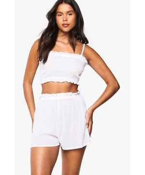 Textured cheesecloth fabric for breathable comfort
        Delicate ruffle trim detailing along the neckline and hem
        Adjustable shoulder straps for a customised fit
        Elasticated crop top design with a flattering square neckline
        Matching shorts with ruffle-trimmed waistband for a coordinated bridal set
    
    Make your wedding morning preparations feel extra special in this charming bridal cami and shorts set. Crafted from soft cotton cheesecloth fabric, this two-piece ensemble combines comfort with bridal elegance. The textured crop top features a feminine square neckline framed by dainty shoulder straps, while the delicate ruffle trim adds a romantic touch to both pieces. Perfect for pre-ceremony photographs or your wedding night, this set can be styled with a lightweight dressing gown and slippers for those precious getting-ready moments. The relaxed fit of the shorts ensures comfort whilst maintaining a flattering silhouette, making this set ideal for honeymoon nights or as part of your trousseau collection. A thoughtful gift for brides-to-be that combines practicality with wedding-day sentiment.