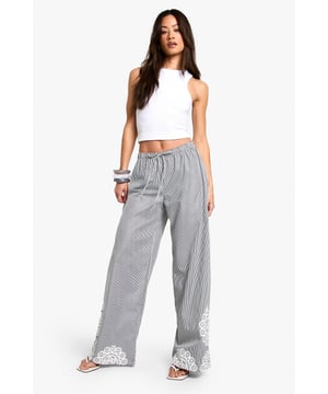 Wide leg trousers featuring delicate floral embroidery detailing at the hem
        Comfortable elasticated waistband with adjustable drawstring tie
        Classic pinstripe pattern throughout for a subtle textured look
        Relaxed, flowing silhouette perfect for taller frames
        Woven fabric that drapes beautifully for effortless movement
    
    These striking wide leg trousers combine casual comfort with distinctive style. The standout floral embroidery at the hem creates a beautiful focal point, while the pinstripe pattern adds a touch of sophistication to your everyday wardrobe. Style with a simple crop top as shown for a balanced silhouette that showcases the dramatic wide leg cut. These trousers are perfect for casual gatherings where you want to make an impression without sacrificing comfort. Pair with flat sandals and a small handbag for daytime events, or dress them up with wedges and statement jewellery for evening occasions. The relaxed fit makes these trousers ideal for family gatherings, brunches with friends, or stylish yet comfortable travel attire. Their versatility allows for countless styling options throughout the seasons.
