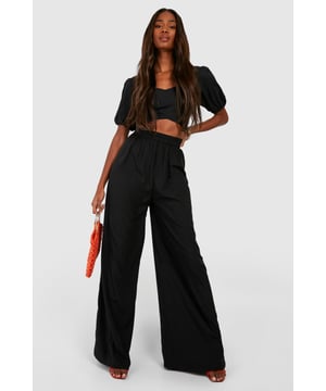Wide leg palazzo design for a dramatic silhouette
        Pleated front detail adds texture and sophistication
        High-waisted fit elongates the legs
        Woven crepe fabric offers a luxurious drape
        Versatile style suitable for various casual occasions
    
    Make a statement with these eye-catching pleat front wide leg palazzo trousers. The dramatic silhouette created by the wide leg design is perfect for those who want to stand out from the crowd. The high-waisted fit not only accentuates your curves but also creates the illusion of longer legs. Pair these trousers with a cropped top, as shown in the image, for a trendy and balanced look. The woven crepe fabric ensures a beautiful drape that moves gracefully with every step. These trousers are ideal for casual events or family gatherings where you want to look effortlessly chic. For a laid-back daytime look, team them with trainers and a simple tee. When the evening calls for something more refined, swap the trainers for heeled sandals and add some statement jewellery to elevate your ensemble. The versatility of these trousers makes them a must-have addition to any fashion-forward wardrobe.
