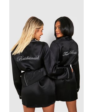 Elegant satin robe with beautiful 'Bridesmaid' embroidery on the back
        Flattering wrap design with self-tie belt to cinch the waist
        Contrast piping detail along the collar, cuffs and edges for a refined finish
        Relaxed fit with wide sleeves for comfortable movement
        Mid-thigh length offering a chic silhouette for pre-wedding preparations
    
    Make your bridesmaid duties even more special with this luxurious satin robe. Perfect for wedding morning preparations, this robe creates a cohesive look for your bridal party whilst ensuring everyone feels pampered and special. The smooth fabric drapes beautifully over the body, whilst the wrap design and adjustable belt allow for a customised fit. Style with matching slippers for getting-ready photos, or wear over delicate lingerie for a touch of glamour. The classic design makes this robe a keepsake that can be treasured long after the big day - ideal for lazy weekend mornings or evening relaxation. A thoughtful gift from the bride that combines practicality with sentiment for those unforgettable pre-ceremony moments.