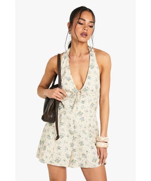 Floral halterneck playsuit with a striking plunging neckline
        Flattering open back design for a breezy summer feel
        Soft cotton fabric ensures comfort throughout the day
        Relaxed fit shorts provide ease of movement for casual occasions
        Tie detail at the neckline adds a feminine touch to the overall look
    
    This charming floral playsuit from Boohoo offers the perfect blend of comfort and style for your casual wardrobe. The halterneck design with its deep V-neckline creates a flattering silhouette, while the open back adds a touch of allure to this otherwise relaxed piece. Style it as seen with chunky bangles and a shoulder bag for daytime outings, or dress it up with strappy sandals and delicate jewellery for garden parties. The playsuit works brilliantly for family gatherings, brunches with friends, or casual weekend adventures. For cooler days, layer with a lightweight denim jacket and trainers for an effortlessly chic ensemble. The versatile design makes it an essential addition to your summer collection, offering both comfort and style in one easy-to-wear piece.