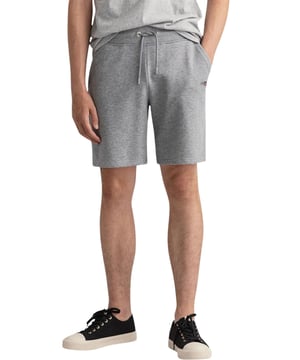 These classic sweat shorts are crafted from a soft cotton blend and tailored for a regular fit. Featuring a ribbed waistband for enhanced comfort, the design includes two front pockets, a single back pocket, and a drawstring waist. Completing the look, the shorts are adorned with a small-scale shield graphic embroidered on the left leg.