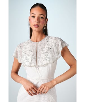Exquisite hand-stitched cape adorned with sparkling gem embellishments and delicate sequin detailing
        Elegant flutter cap sleeves create a graceful silhouette that frames the shoulders beautifully
        Stunning open back design with sheer panels adds a contemporary touch to this traditional bridal accessory
        Intricate beadwork catches the light with every movement for a truly magical effect
        Versatile piece that can be styled with various wedding gown silhouettes for a personalised bridal look
    
    Make a breathtaking entrance on your special day with this enchanting bridal cape from Coast. The delicate hand-stitched detailing and carefully placed gem embellishments create a halo of radiance around your shoulders, adding a touch of glamour to your wedding ensemble. The thoughtfully designed open back ensures your gown remains the centrepiece whilst the cape adds dimension and visual interest. Style with a sleek updo and drop earrings as seen on our model to showcase the intricate neckline, or wear with flowing locks for a more romantic aesthetic. Perfect for the ceremony and photographs, this cape transitions beautifully from the aisle to the reception, offering a sophisticated layer that can be removed later to reveal a second look for evening celebrations. A truly special accessory that will become a cherished keepsake of your wedding day.
