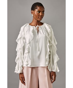 Luxurious satin blouse with dramatic cascading frills along the sleeves
        Elegant round neckline with delicate tie detail
        Relaxed silhouette with gathered detailing at the shoulders
        Statement long sleeves with beautiful ruffle embellishment
        Versatile design suitable for both formal occasions and sophisticated daywear
    
    This captivating Satin Frill Blouse from Coast presents a perfect balance of drama and refinement. The sumptuous satin fabric catches the light beautifully whilst the cascading frills along the sleeves create a striking visual impact. Style with wide-leg trousers as shown for an elegant ensemble perfect for summer weddings or race day events. For evening occasions, pair with a tailored pencil skirt and strappy heels to showcase the blouse's exquisite detailing. The relaxed fit and gathered neckline offer both comfort and sophistication, making this piece equally suitable for formal celebrations or elevated daywear when paired with smart trousers and court shoes. This versatile blouse will become a treasured addition to your occasion wardrobe, offering countless styling possibilities whilst maintaining that signature Coast elegance.