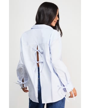 Oversized fit with classic collar and button-through front for a relaxed silhouette
        Distinctive bow-tie back detail creates a feminine twist on the traditional shirt
        Long sleeves with button cuffs offer versatility for year-round styling
        Cotton fabric provides breathable comfort for all-day wear
        Subtle split back design adds movement and contemporary flair
    
    This Warehouse oversized shirt reinvents the classic button-down with its striking bow-back detail. The relaxed fit creates an effortlessly chic look that works beautifully with straight-leg jeans and flats for casual outings. For a more polished ensemble, try half-tucking the front into high-waisted trousers and adding a structured tote. The cotton construction ensures comfort whilst maintaining a crisp appearance throughout the day. Perfect for family gatherings or weekend brunches, this versatile piece transitions seamlessly from daytime casual to evening drinks when paired with statement earrings and ankle boots. The thoughtful back detail adds interest when layered under jumpers or jackets, making this shirt a standout addition to your wardrobe that works across multiple seasons.