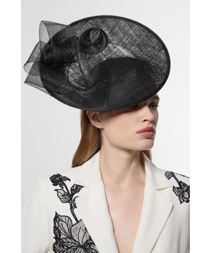 Make a captivating entrance with this Karen Millen asymmetric fascinator, designed to turn heads at your next special occasion. The architectural silhouette features a gracefully curved disk base adorned with flowing mesh detailing that creates movement and drama. Style with a tailored dress or jumpsuit in a complementary tone for race day sophistication, or pair with an elegant evening ensemble for wedding celebrations. The fascinator works with sleek, pulled-back hair to showcase its artistic structure, though it equally complements soft waves for a more romantic aesthetic. This versatile headpiece transitions effortlessly from daytime formal events to evening soires, adding that perfect finishing touch to your carefully curated outfit.  Striking asymmetric design with disk detailing Delicate mesh overlay Sculptural wave effect Secure headband fitting for comfortable all-day wear Versatile statement piece that complements both updo and loose hairstyles