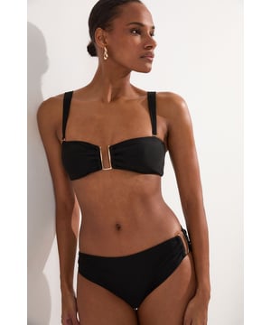 These sophisticated Karen Millen bikini bottoms bring a touch of luxury to your beachwear collection. The striking gold trim adds a refined accent that catches the light beautifully as you lounge poolside or stroll along the shore. Pair with the coordinating bandeau top for a cohesive look that's perfect for your summer getaway. Style with oversized sunglasses and a flowing kaftan for elegant poolside glamour, or team with a linen shirt and sandals when heading to a beachside lunch. These bottoms offer the perfect balance of comfort and sophistication for your next sun-soaked holiday.   Distinctive gold-tone trim detail on the side Mid-rise design offering comfortable coverage and a flattering silhouette Soft, stretchy fabric Sleek, minimalist design that pairs beautifully with the matching bandeau top  Matching piece sold separately.