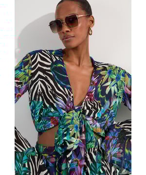 Make a statement at your next beach destination with this bold wrap top from Karen Millen. The eye-catching mixed print combines tropical florals with striking animal motifs for a head-turning effect. The lightweight georgette fabric drapes beautifully, while the wrap design with front tie detail creates a flattering silhouette that works brilliantly over swimwear or paired with the matching wide-leg trousers as seen on our model. Style with oversized sunglasses and gold-toned jewellery for poolside sophistication, or throw on with denim shorts and sandals for casual beachside lunches. This versatile piece transitions effortlessly from daytime beach lounging to sunset cocktails, simply add strappy sandals and a clutch bag to complete your holiday ensemble.  Striking floral and animal print wrap top in lightweight viscose georgette fabric Flattering plunging V-neckline with front tie detail creating a chic cropped silhouette Elegant long sleeves with subtle flare at the cuffs for added movement Versatile beach wrap design perfect for layering over swimwear Part of the exclusive Karen Millen Tall collection, designed with longer proportions