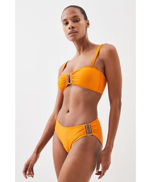 This Karen Millen bikini top combines contemporary design with practical versatility. The standout gold-tone hardware creates a luxurious focal point whilst the detachable straps offer two distinct looks - wear as a classic bandeau for minimal tan lines or attach the straps for additional support during active beach days. The gathered fabric detail adds a touch of sophistication that distinguishes this piece from ordinary swimwear. Perfect for making a statement whilst lounging poolside at exclusive resorts or during sun-soaked coastal holidays. Style with oversized sunglasses and delicate gold jewellery for a coordinated look, or layer under a sheer kaftan for elegant transitions from beach to bar. This bikini top effortlessly balances fashion-forward design with functional beachwear, ensuring you remain stylish whatever your holiday activities.   Elegant bandeau-style bikini top featuring a gold-tone metal trim at the front Versatile detachable straps allow for multiple styling options Soft gathered fabric detail Secure fit with comfortable stretch fabric Coordinating bottoms available to complete this refined beach ensemble  Matching piece sold separately.
