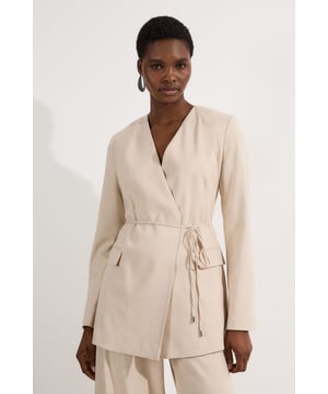 This Karen Millen blazer redefines casual sophistication with its clean, collarless neckline and wrap-style front. The tie waist detail allows you to customise the fit to your preference, creating a beautifully feminine silhouette that works wonderfully for daytime engagements. Style with the coordinating wide-leg trousers as seen on our model for an effortlessly chic co-ord look perfect for family gatherings or brunch dates. For more casual styling, pair with your favourite denim and a simple t-shirt, finishing with trainers for an elevated everyday ensemble. The neutral tone makes this blazer an incredibly versatile wardrobe staple that transitions seamlessly from office to weekend wear, while the regular fit ensures comfort without compromising on style.  Collarless design with elegant wrap-front styling for a contemporary silhouette Tailored marl fabric with slight stretch for comfortable all-day wear Sophisticated tie waist detail that creates a flattering, defined shape Long sleeves with subtle structured shoulders for a polished look Versatile regular fit designed specifically for petite frames at approximately 75cm in length