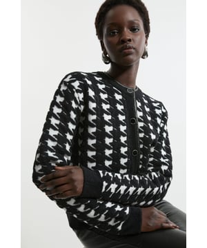 Elevate your outer layers with an understated yet elegant jacket, with a figure hugging silhouette, a high neckline, and button detailing. The houndstooth pattern brings a sense of traditional tailoring, while the faux leather trims contrast the texture of the knit boucle fabric, making a dynamic piece to keep reaching for. Style it with anything, from tailored trousers, to jeans for an elevated look that will take you seamlessly from day to night. Boucle Jacquard Houndstooth Knit Faux Leather Trim Jacket High Quality, Soft Boucle Fabric Warm, Fitted Silhouette Classic Houndstooth Pattern Complementary, Metallic Buttons Formal, High Neckline Contrasting Faux Leather Trims Button Front FasteningMatching piece sold separately.