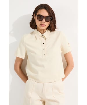 This Karen Millen denim shirt reimagines casual dressing with its contemporary half-button design and relaxed silhouette. The cropped length works brilliantly with high-waisted trousers, creating a balanced proportion that flatters the figure. This shirt can be styled with tailored linen trousers and leather sandals for a refined daytime look, or for cooler evenings layer it under a lightweight blazer. This versatile piece transitions seamlessly from casual coffee dates to informal garden parties, simply accessorise with statement sunglasses and delicate jewellery to customise your look for any occasion.   Relaxed fit denim shirt Classic collar detail with short sleeves Versatile cropped length perfect for high-waisted bottoms Metal button detailing adds subtle sophistication to this casual piece  Matching piece sold separately.