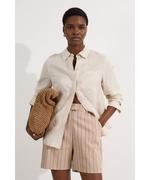 These Karen Millen tailored city shorts combine sophistication with casual comfort for effortless daywear styling. The distinctive stripe pattern with subtle sparkle threads creates visual interest while maintaining versatility. Style them with a crisp white t-shirt and an oversized blazer for a polished weekend brunch look, or pair with a lightweight knit and trainers for shopping trips and casual gatherings. The structured silhouette and linen blend fabric make these shorts perfect for warm-weather socialising without compromising on style. For a coordinated summer ensemble, match with flat sandals and a crossbody bag, adding sunglasses for a touch of chic practicality. These shorts transition seamlessly from daytime family gatherings to early evening garden parties, offering both comfort and refined style.  Tailored city shorts featuring a distinctive sparkle stripe pattern for a touch of subtle glamour Crafted with linen blend fabric for breathable comfort during warm weather Elegant gold-tone buckle detail at the waistband adds a refined finishing touch Practical side pockets for convenient storage of small essentials Versatile 45cm length offering a flattering fit that pairs beautifully with various tops  Matching piece available, sold separately.
