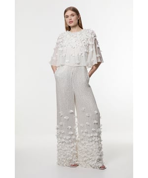 This show-stopping Karen Millen jumpsuit transforms any formal occasion into your personal runway. The delicate angel sleeves flutter gracefully with every movement, whilst the crystal embellishments catch the light from every angle, ensuring all eyes remain on you. Perfect for weddings, races, or black-tie events, this piece requires minimal accessorising; pair it with metallic strappy heels and a sleek clutch for maximum impact. The wide-leg silhouette offers comfort and dramatic flair, allowing for effortless movement throughout your event. For cooler evenings, drape a tailored blazer over your shoulders for an additional touch of sophistication. The jumpsuit's thoughtful design combines the elegance of eveningwear with the practicality of trousers, making it a versatile alternative to the traditional occasion dress.   Stunning crystal appliqu detailing across the bodice and legs Elegant angel sleeves offer graceful movement and sophisticated coverage Crew neckline Wide-leg design Intricate beadwork from top to bottom for a luxurious finish