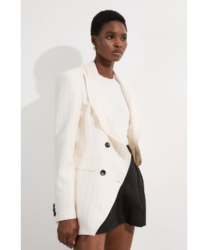 This Karen Millen tailored jacket embodies contemporary sophistication with its distinctive pinstripe pattern and waisted silhouette. The double-breasted fastening creates a structured look that defines the figure beautifully, whilst the classic collar adds a touch of traditional tailoring. Style with the matching trousers for a coordinated power suit, perfect for important meetings or formal occasions. For evening events, pair with a sleek camisole and tailored shorts as shown, adding statement jewellery and heels for a modern take on occasion dressing. The versatile design transitions effortlessly from boardroom to social gatherings, making it an essential investment piece for the discerning wardrobe.  Double-breasted design with contrasting buttons for a sophisticated silhouette Elegant pinstripe pattern adds subtle texture and visual interest Tailored waist creates a flattering feminine shape Classic collared neckline offers timeless appeal Long sleeves with button detail for refined finishing  Matching piece sold separately.