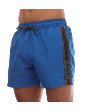 Mens Emporio Armani EA7 Logo Tape Swim Shorts in blue.- Elasticated waistband.- Two side slash pockets.- Back pocket.- Logo print to the side.- 100% Polyester.- Ref: 7M000535UB054