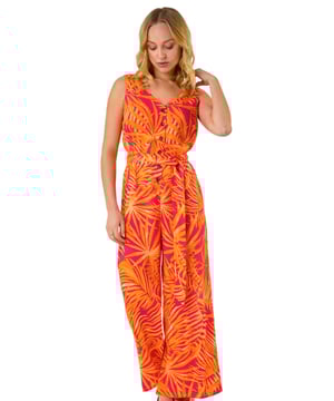 Dusk Palm Print Belted Jumpsuit from Roman. Get ready to make a statement in this chic palm print jumpsuit for the upcoming Spring/Summer season. Featuring a flattering v-neck and sleeveless design, this woven jumpsuit is perfect for sunny days. The belted waist detail adds a touch of elegance and ensures a great fit. Complete your look with sandals and a trendy denim jacket for effortless style!