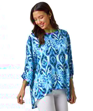 Ikat Print Tunic Top from Roman. Unleash your inner boho chic with this stunning all over ikat print tunic. Featuring a unique overlay design and a classic round neckline, this tunic is perfect for the Spring/Summer season. The 3/4 sleeves add a stylish touch to this standout piece. Pair with jeans and sandals for an effortless and casual look.