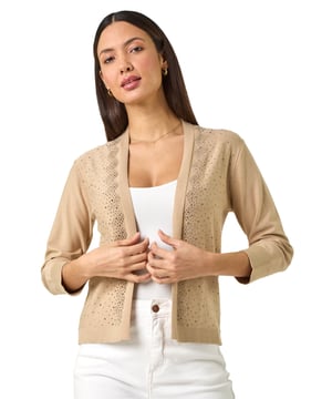 Sparkle Hotfix Knit Shrug from Roman. Add a touch of glamour to your Spring/Summer outfits with this hotfix 3/4 length sleeve shrug. Designed with an elegant edge-to-edge front, this shrug is perfect for layering over a dress for a special occasion or evening out. The hotfix detailing on the sleeves adds a sophisticated sparkle, making it a versatile and stylish piece to elevate any outfit.