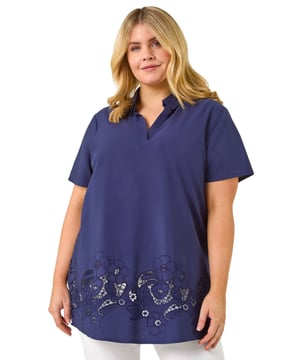 Curve Floral Cut Out Woven Top from Roman. This V-neck top with a collar features short sleeves and a flattering below-hip length. The floral cut out detail along the hem adds a delicate, feminine touch to the design. Crafted from comfortable woven fabric, it's perfect for warm weather. Pair it with shorts and sandals for a stylish, breezy look that’s ideal for casual outings or summer days.